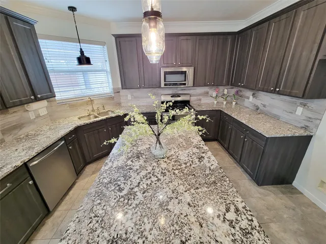 a kitchen with granite countertop kitchen island a sink counter space and stainless steel appliances
