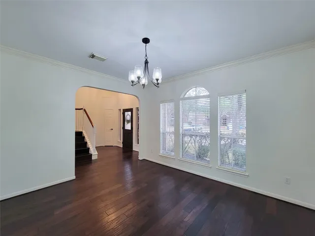 a view of a room with wooden floor chandelier and windows