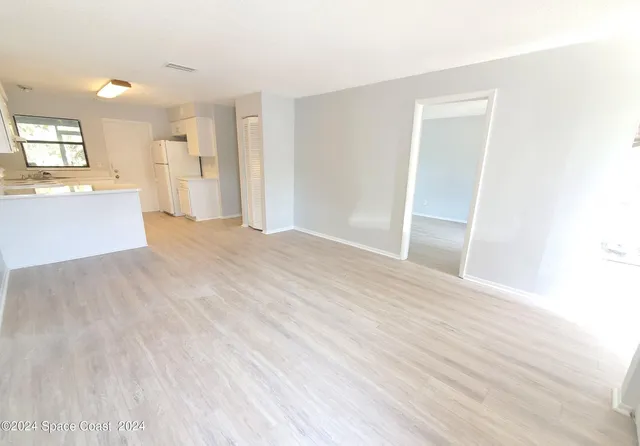 a view of a big room with wooden floor and windows