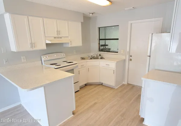 a kitchen with a sink a stove a refrigerator and white cabinets