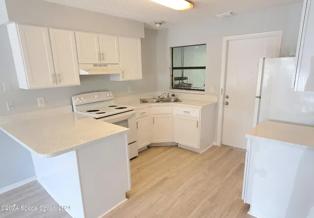 a kitchen with a sink a stove a refrigerator and white cabinets