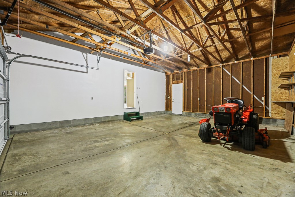 2642 Blake Road Wadsworth, OH 44281 - Photo 43 of 46 Spacious garage featuring a concrete floor, exposed wood ceiling trusses, white painted walls, and built-in shelving