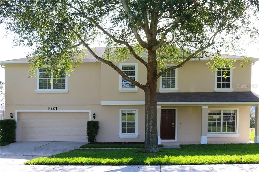 a front view of a house with a garden and trees