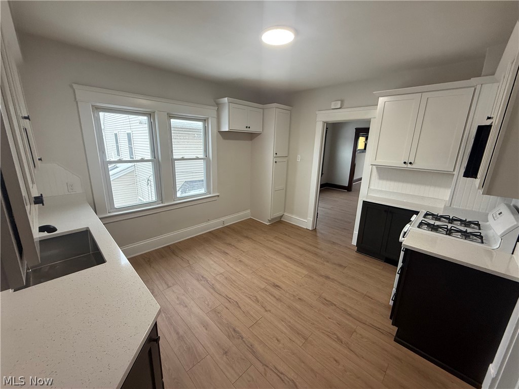 3612 Riverside Avenue Cleveland, OH 44109 - Photo 6 of 22 Kitchen featuring wood-finish flooring, two large windows, white shaker cabinetry, dark lower cabinetry, and light-toned countertops