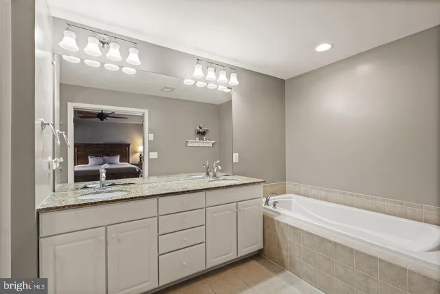 a bathroom with a granite countertop sink mirror and bathtub