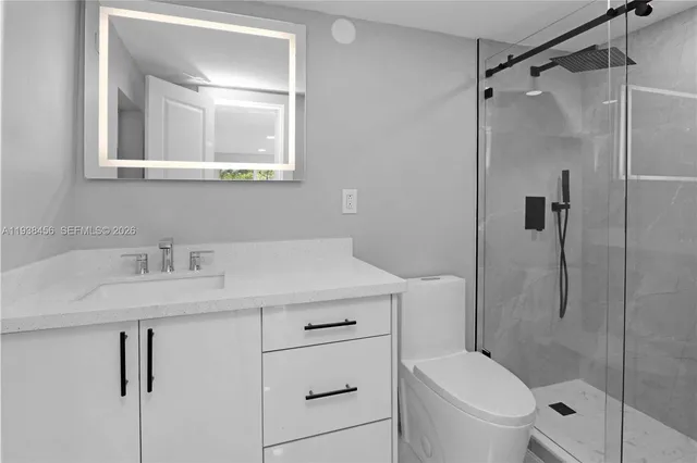 a bathroom with a granite countertop sink toilet a mirror and shower