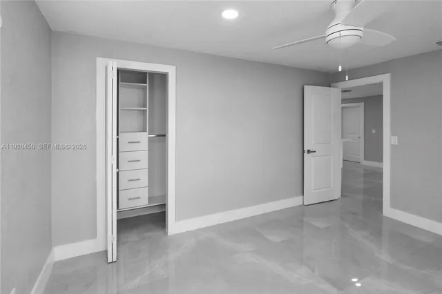 an empty room with closet and a ceiling fan