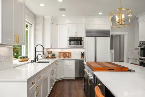 a kitchen with stainless steel appliances a sink a stove a refrigerator cabinets and living room view