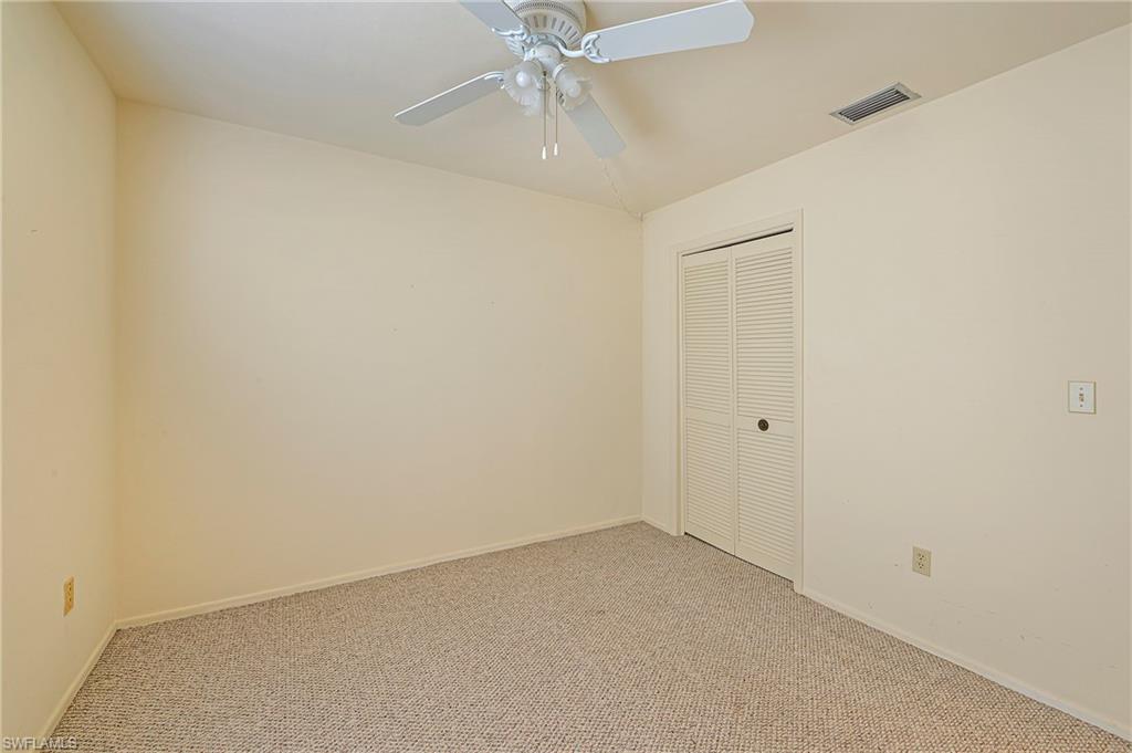 1007 Pine Isle Lane, Unit 1007 Naples, FL 34112 - Photo 13 of 20 an empty room with a ceiling fan and carpet