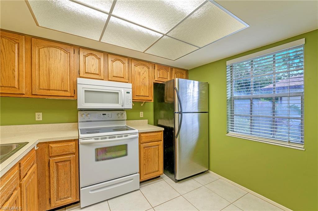 1007 Pine Isle Lane, Unit 1007 Naples, FL 34112 - Photo 3 of 20 a kitchen with a stove top oven cabinets and a refrigerator