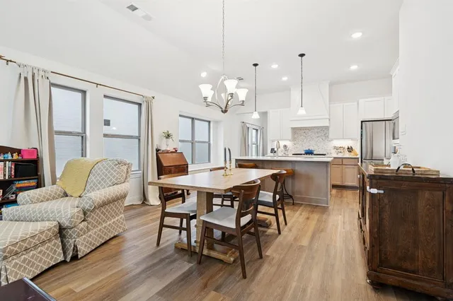 a living room with furniture kitchen view and a wooden floor