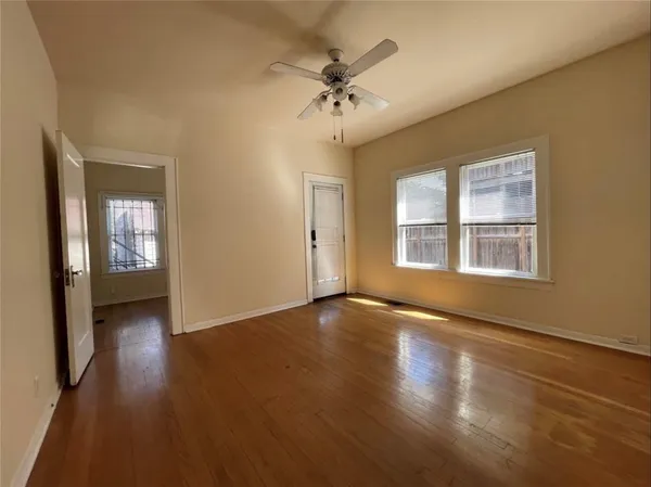 a view of an empty room with wooden floor and a window