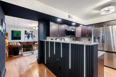 a kitchen with stainless steel appliances a refrigerator and a wooden floor