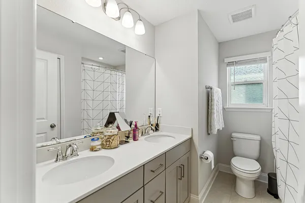 a bathroom with a toilet sink double vanity and mirror