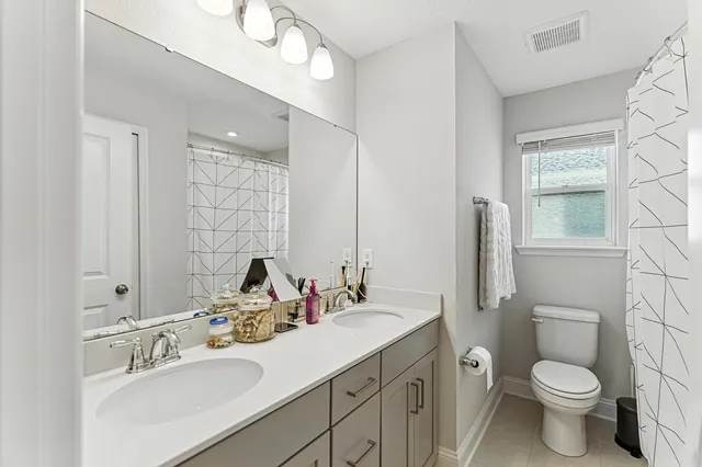 a bathroom with a toilet sink double vanity and mirror