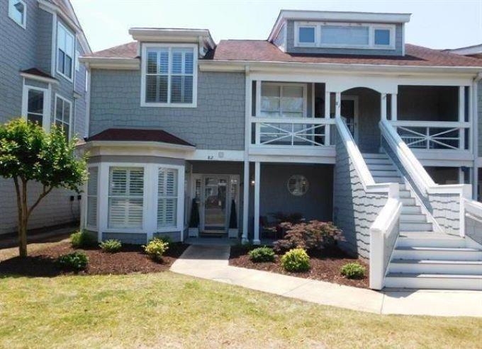 View of front of home with a front lawn, a porch, and stairway