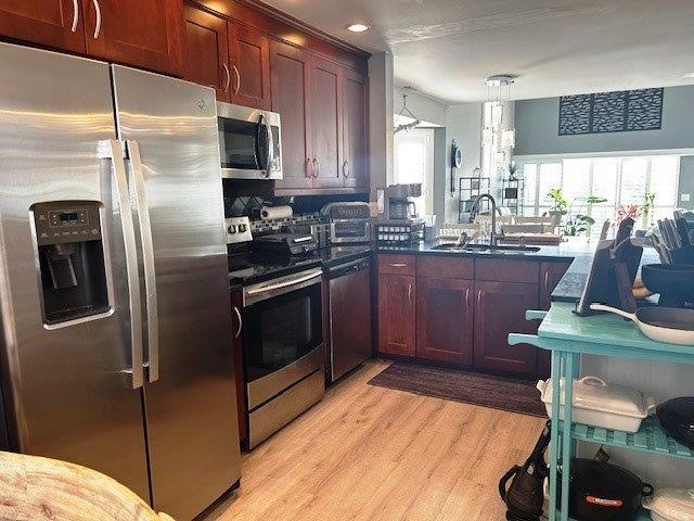 4396 Baldwin Avenue, Unit 82 Little River, SC 29566 - Photo 9 of 31 Kitchen featuring stainless steel appliances, decorative light fixtures, light wood-style floors, a peninsula, and dark brown cabinets