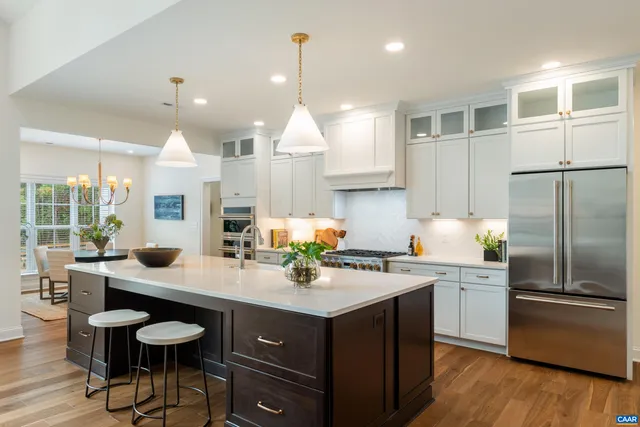 a kitchen with stainless steel appliances kitchen island granite countertop a refrigerator and a sink
