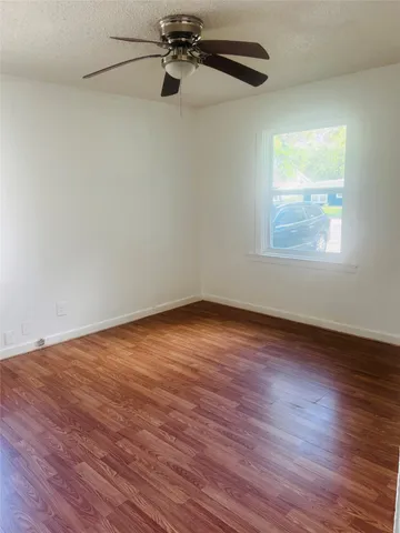 an empty room with wooden floor cabinet and windows
