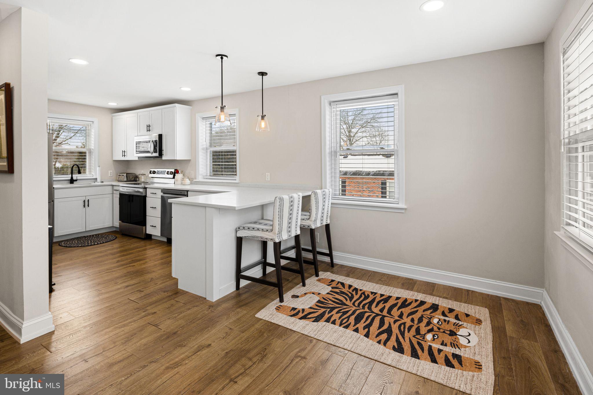 910 Edann Road Oreland, PA 19075 - Photo 13 of 26 a open kitchen with stainless steel appliances granite countertop a stove top oven a refrigerator a dining table and chairs with wooden floor