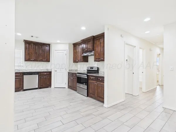 a large kitchen with stainless steel appliances granite countertop a stove a sink dishwasher a refrigerator and a stove