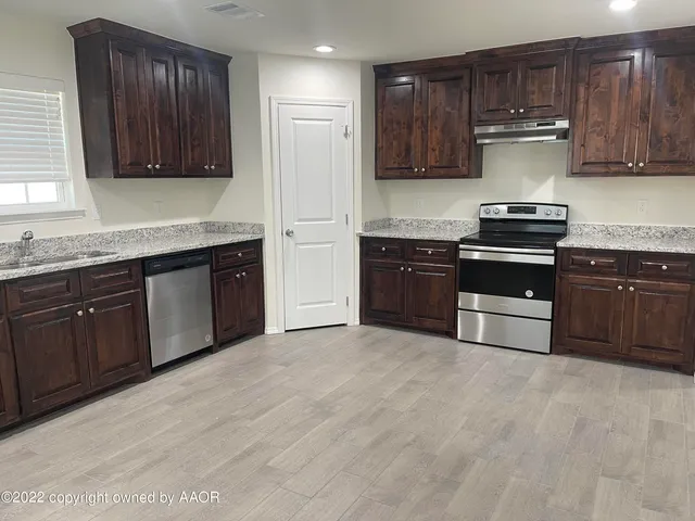 a kitchen with stainless steel appliances granite countertop wooden cabinets stove top oven and sink