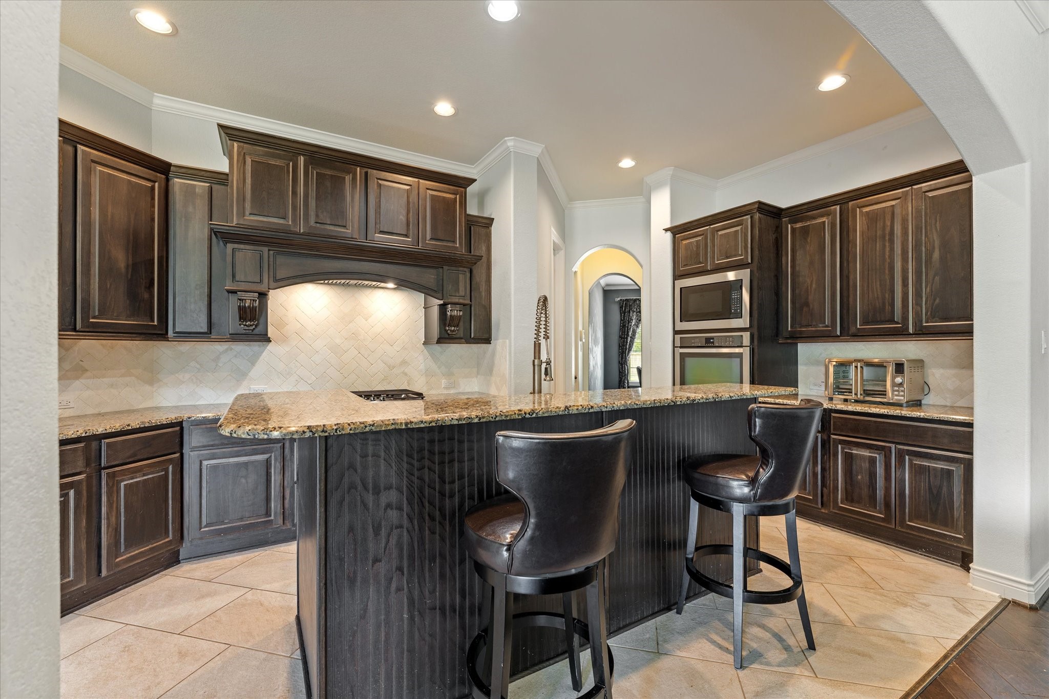2506 Barclay Lake Lane Spring, TX 77388 - Photo 9 of 35 Where gatherings happen, a substantial island with bar seating, granite counters, herringbone backsplash, and rich cabinetry make this kitchen the true heart of the home.