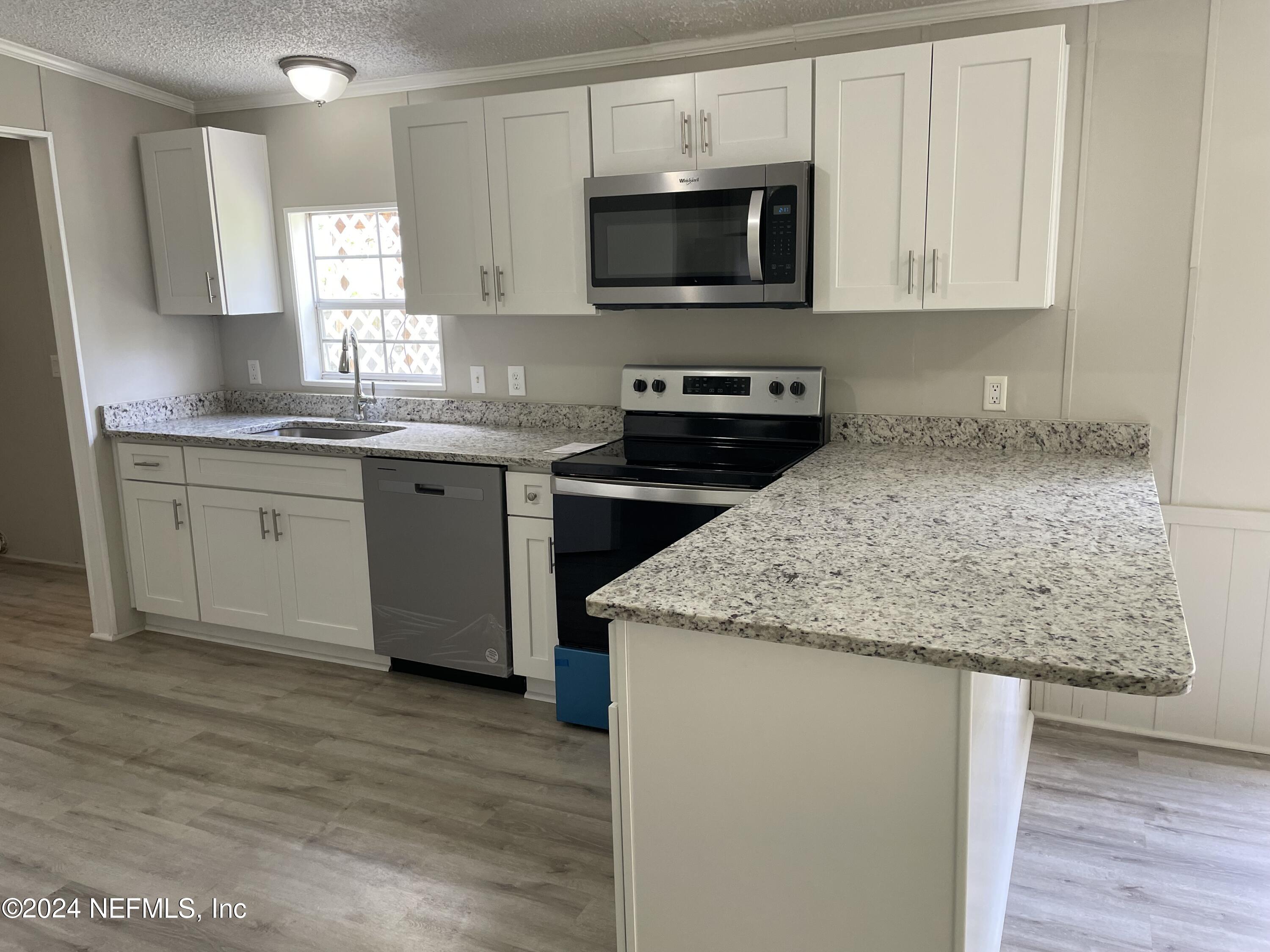43621 Ratliff Road Callahan, FL 32011 - Photo 11 of 16 a kitchen with granite countertop a sink and a stove top oven