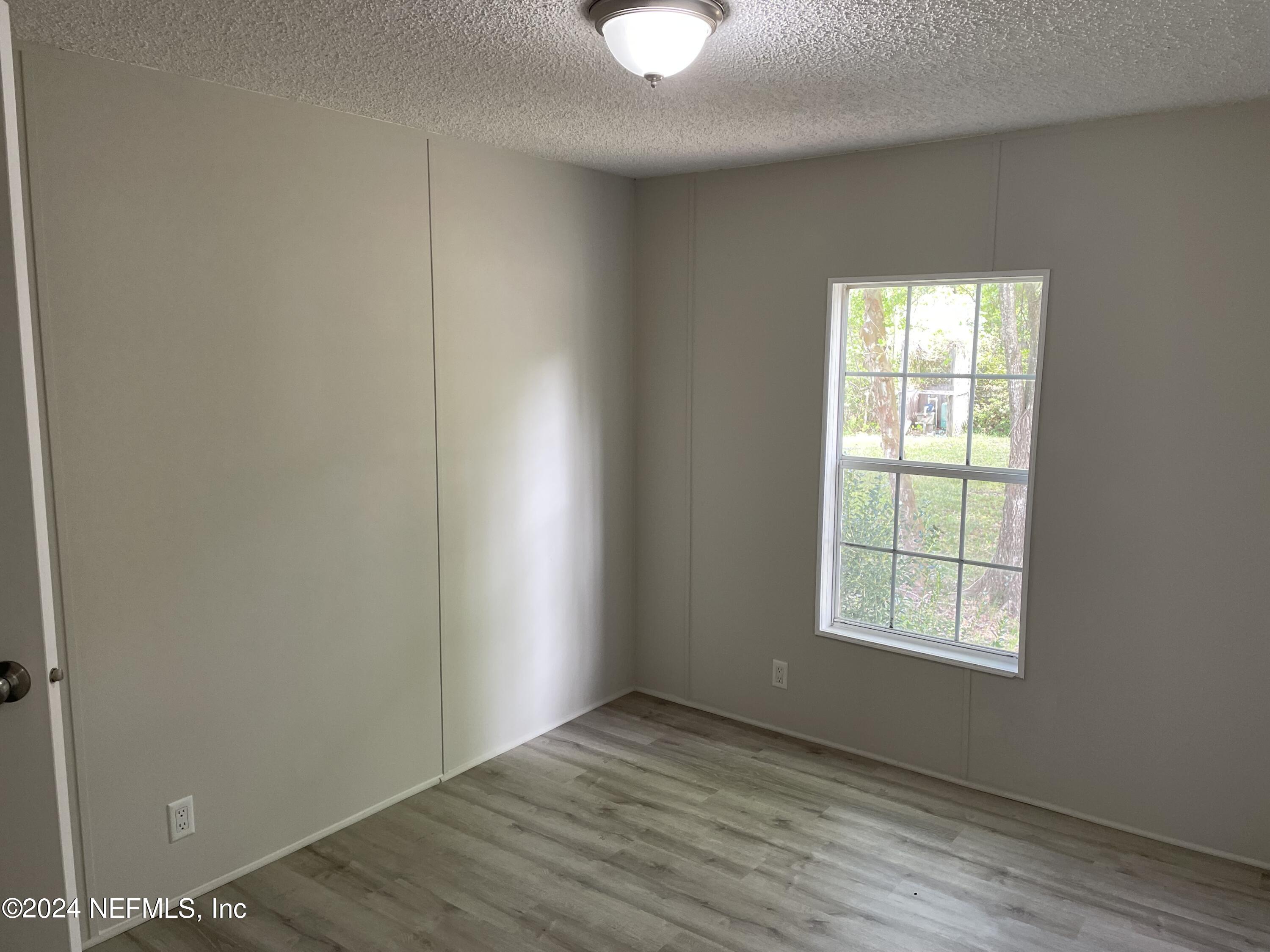 43621 Ratliff Road Callahan, FL 32011 - Photo 12 of 16 an empty room with wooden floor closet and windows