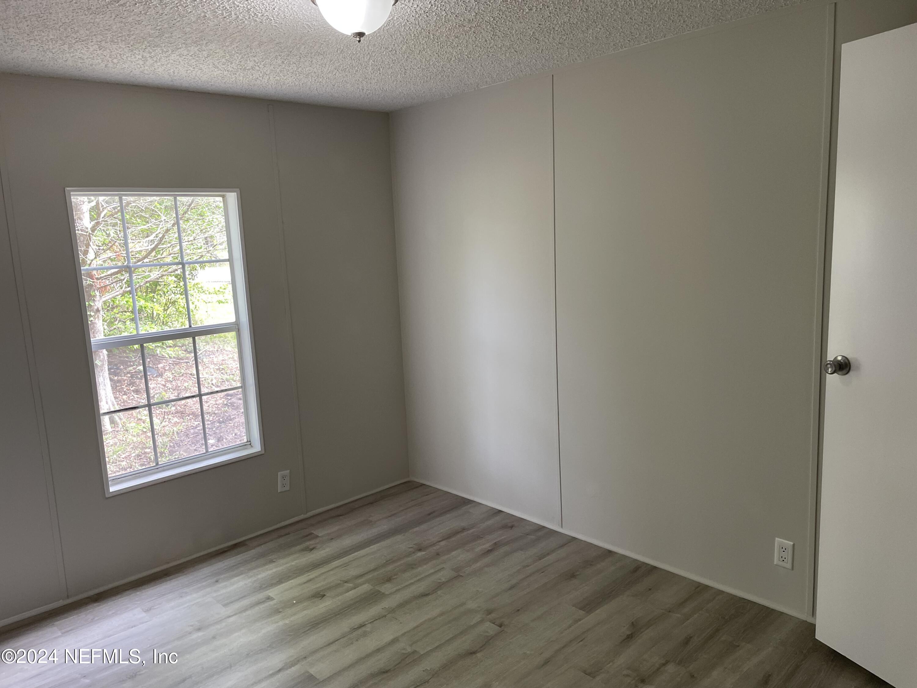 43621 Ratliff Road Callahan, FL 32011 - Photo 14 of 16 an empty room with wooden floor cabinet and windows