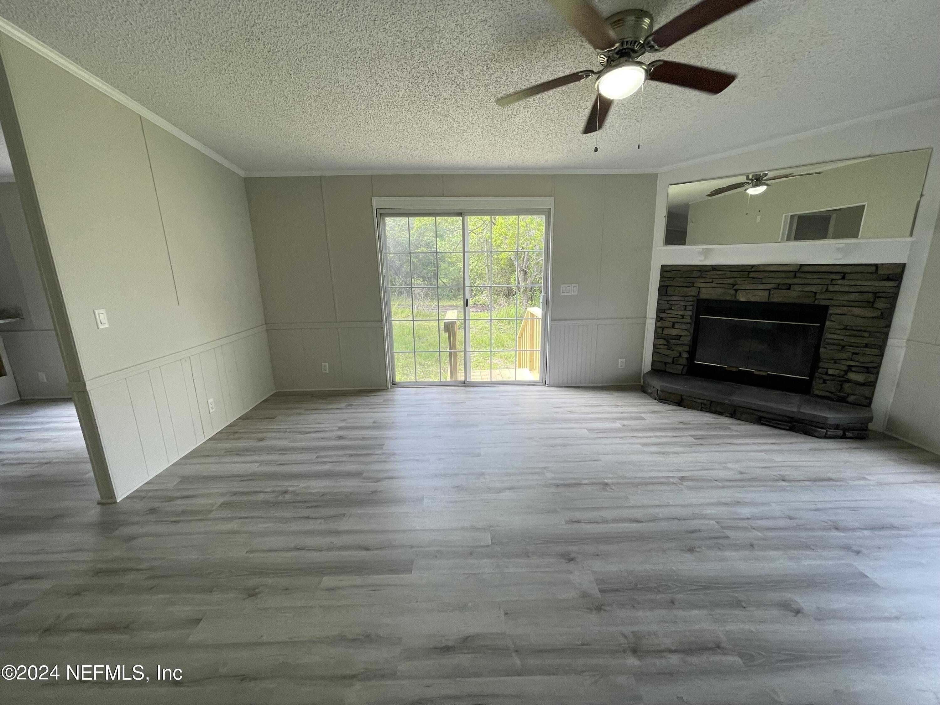 43621 Ratliff Road Callahan, FL 32011 - Photo 15 of 16 a view of an empty room with wooden floor fireplace and a window