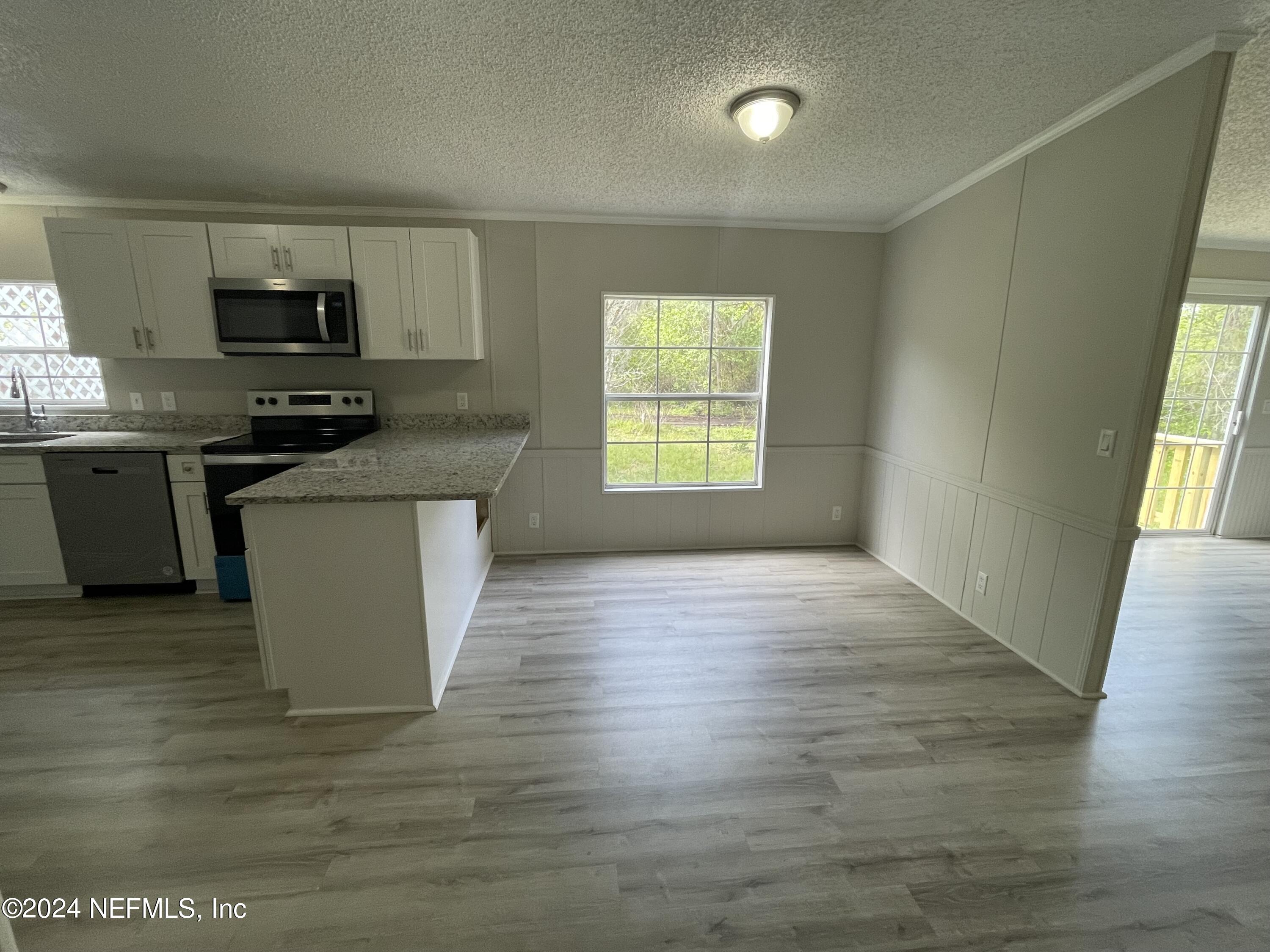 43621 Ratliff Road Callahan, FL 32011 - Photo 6 of 16 a kitchen with stainless steel appliances granite countertop a stove a sink and a microwave