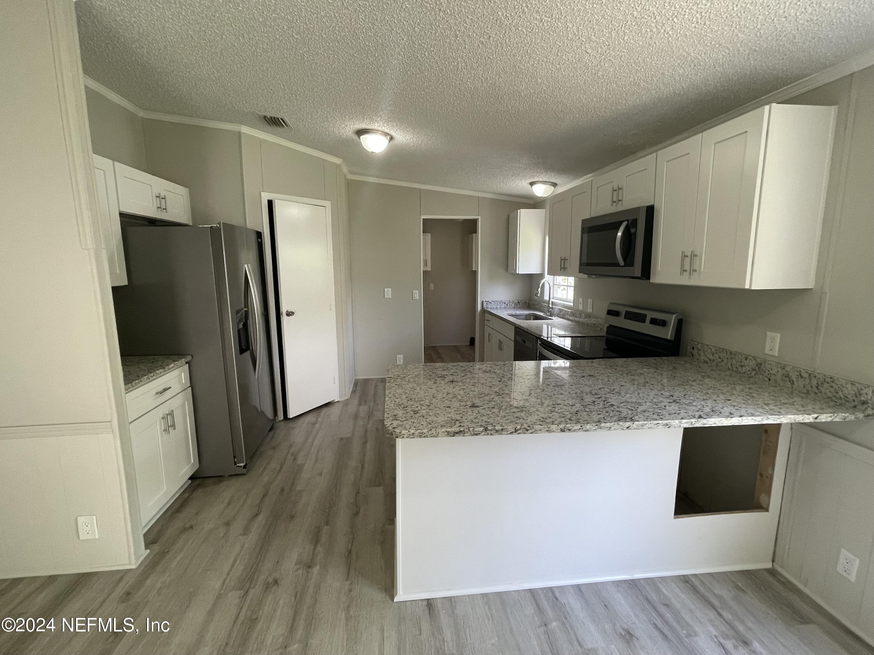 43621 Ratliff Road Callahan, FL 32011 - Photo 9 of 16 a kitchen with stainless steel appliances granite countertop a refrigerator a stove top oven a sink and dishwasher