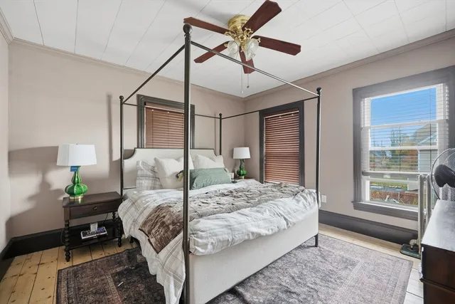a bedroom with a bed next to a window with a potted plant on a dresser