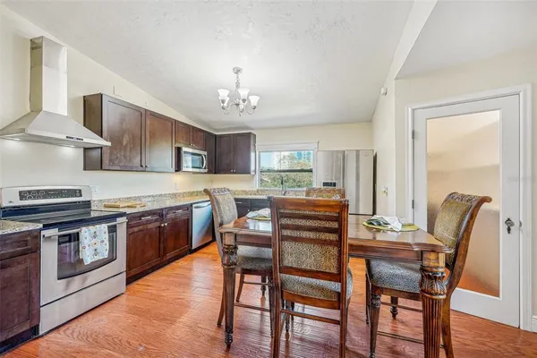 a kitchen with stainless steel appliances granite countertop a stove a sink a dining table and chairs