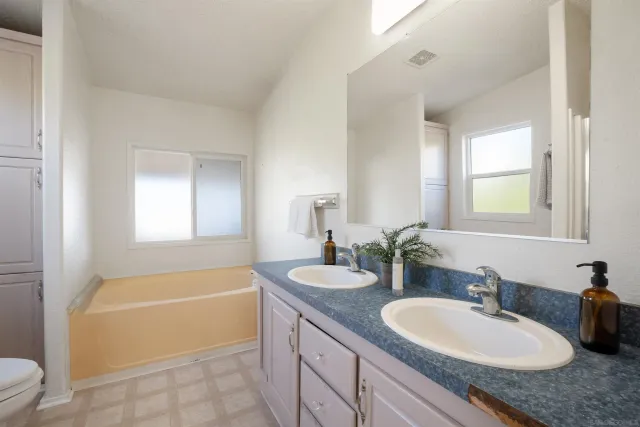 a bathroom with a granite countertop tub a sink and a mirror