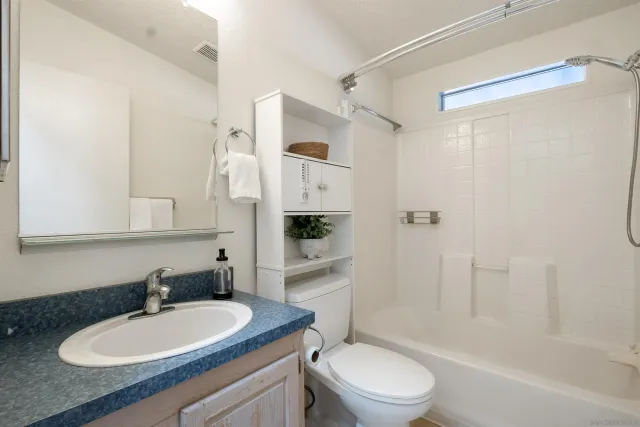 a bathroom with a granite countertop sink toilet a mirror and shower