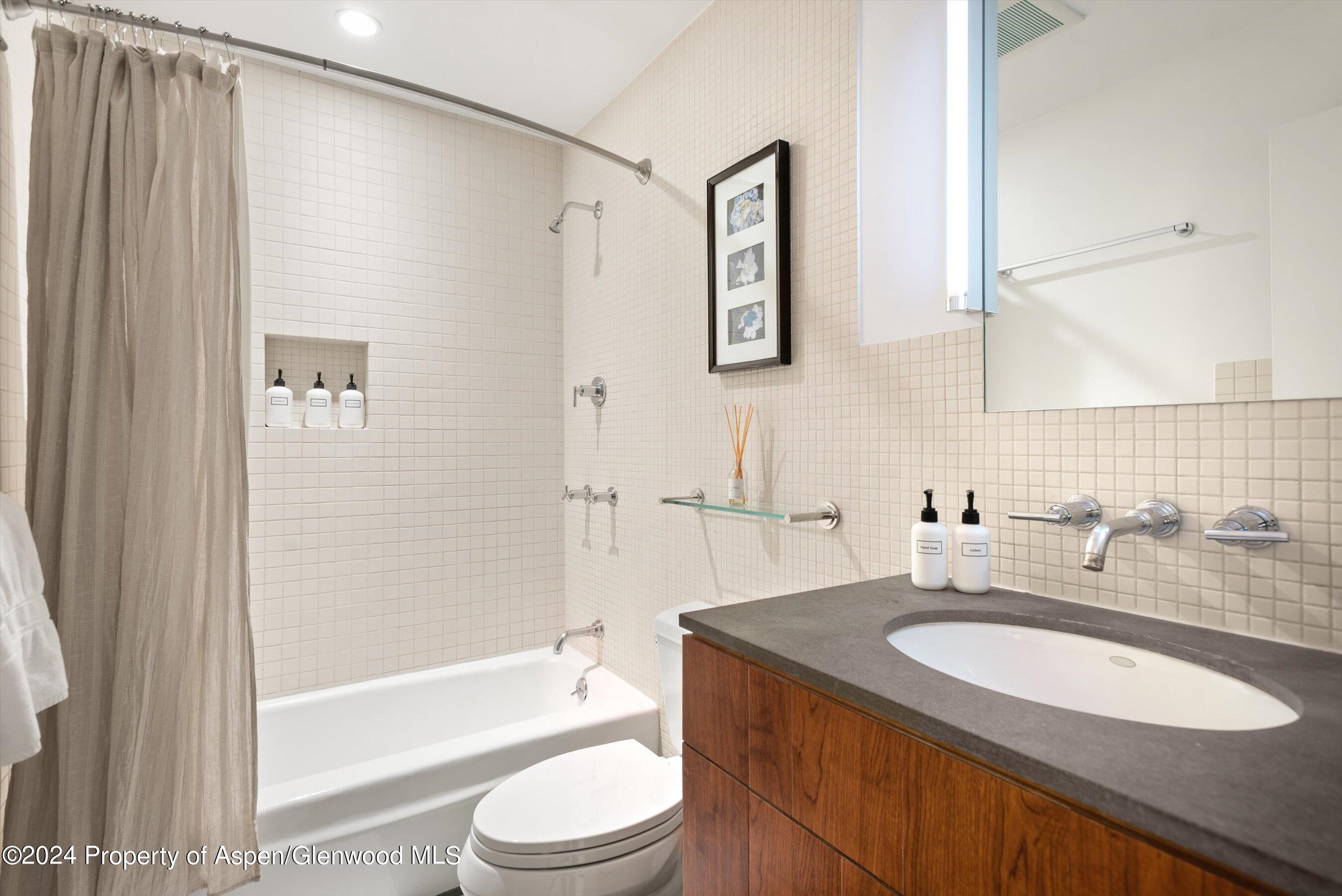 100 East Dean Street, Unit 1E Aspen, CO 81611 - Photo 7 of 10 a bathroom with a granite countertop sink toilet and shower