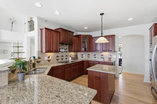 a large kitchen with kitchen island a stove a sink a oven a dining table and chairs