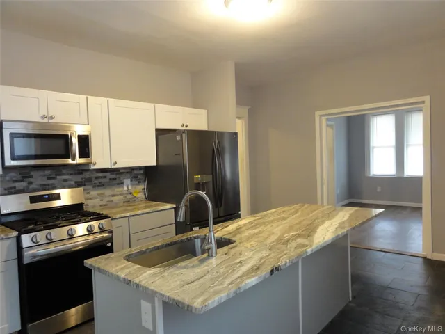 a kitchen with granite countertop a refrigerator stove and microwave