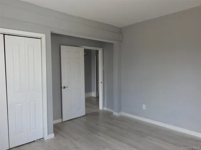 a view of an empty room with closet and wooden floor