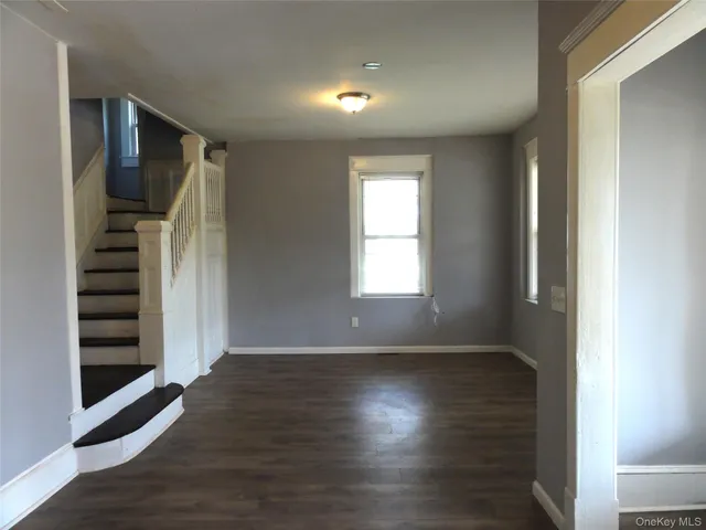 an empty room with wooden floor closet and windows