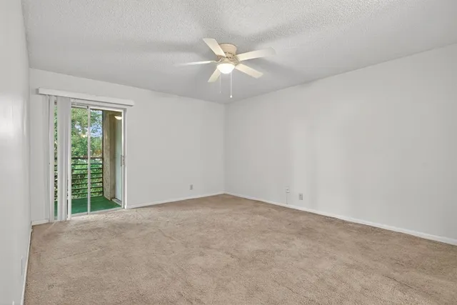an empty room with a ceiling fan and window