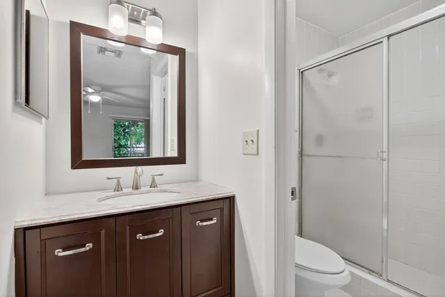 a bathroom with a granite countertop sink toilet and shower