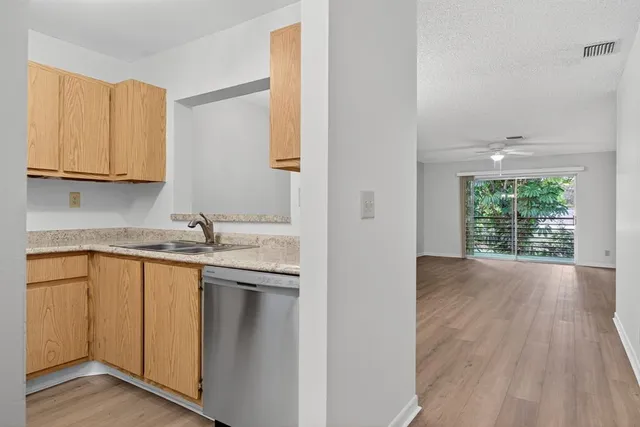a kitchen with stainless steel appliances granite countertop a sink and cabinets with wooden floor