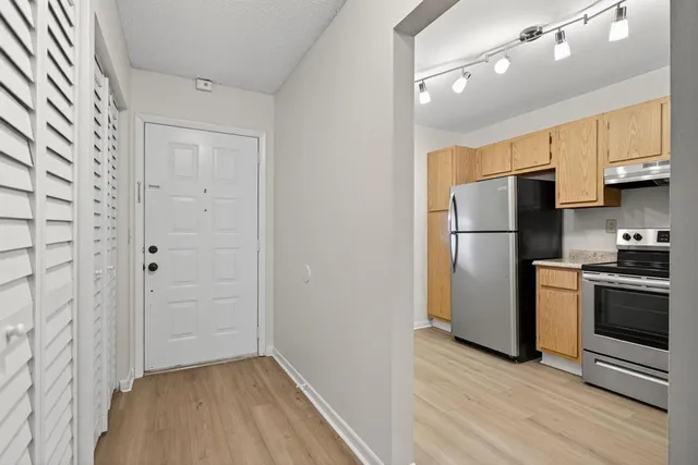an empty room with wooden floor and a kitchen