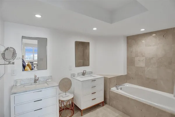 a bathroom with a granite countertop sink mirror and a bathtub
