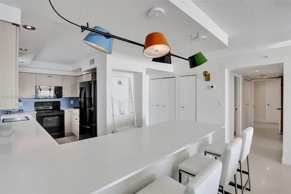 a kitchen with stainless steel appliances kitchen island granite countertop a table chairs and a refrigerator
