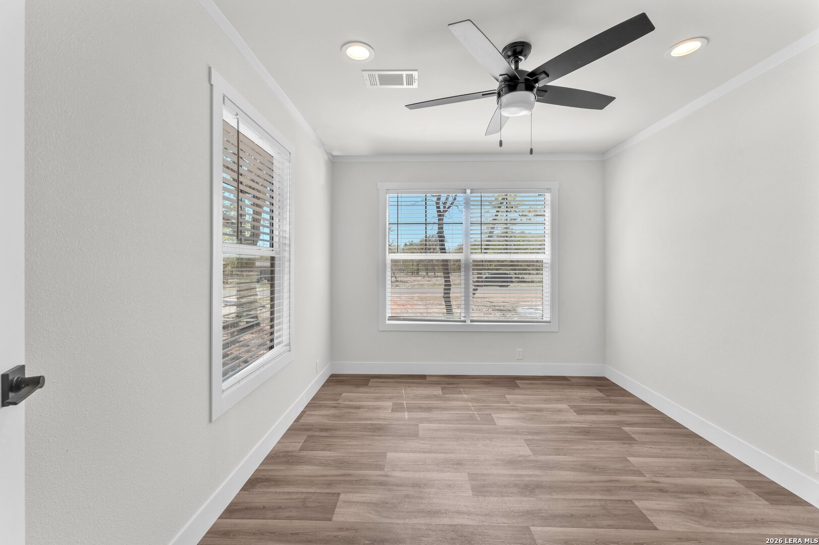 2218 Stevens Road Somerset, TX 78069 - Photo 13 of 24 an empty room with wooden floor chandelier fan and windows