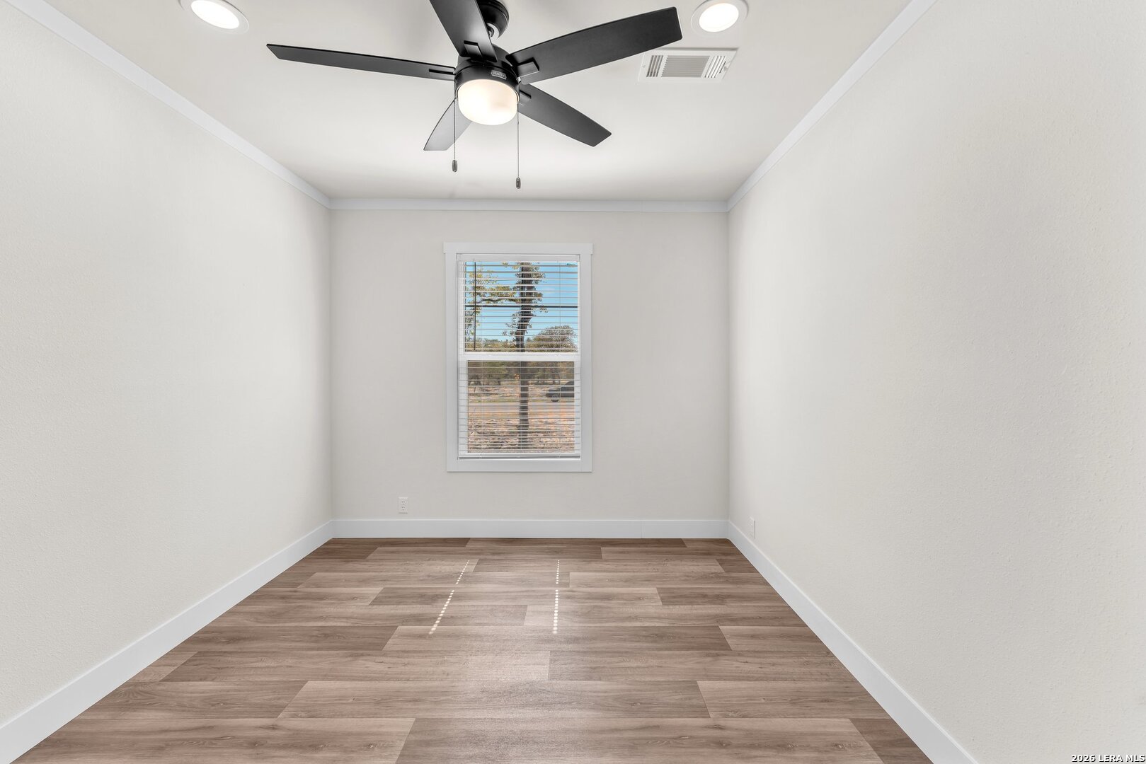 2218 Stevens Road Somerset, TX 78069 - Photo 19 of 24 an empty room with wooden floor ceiling fan and windows